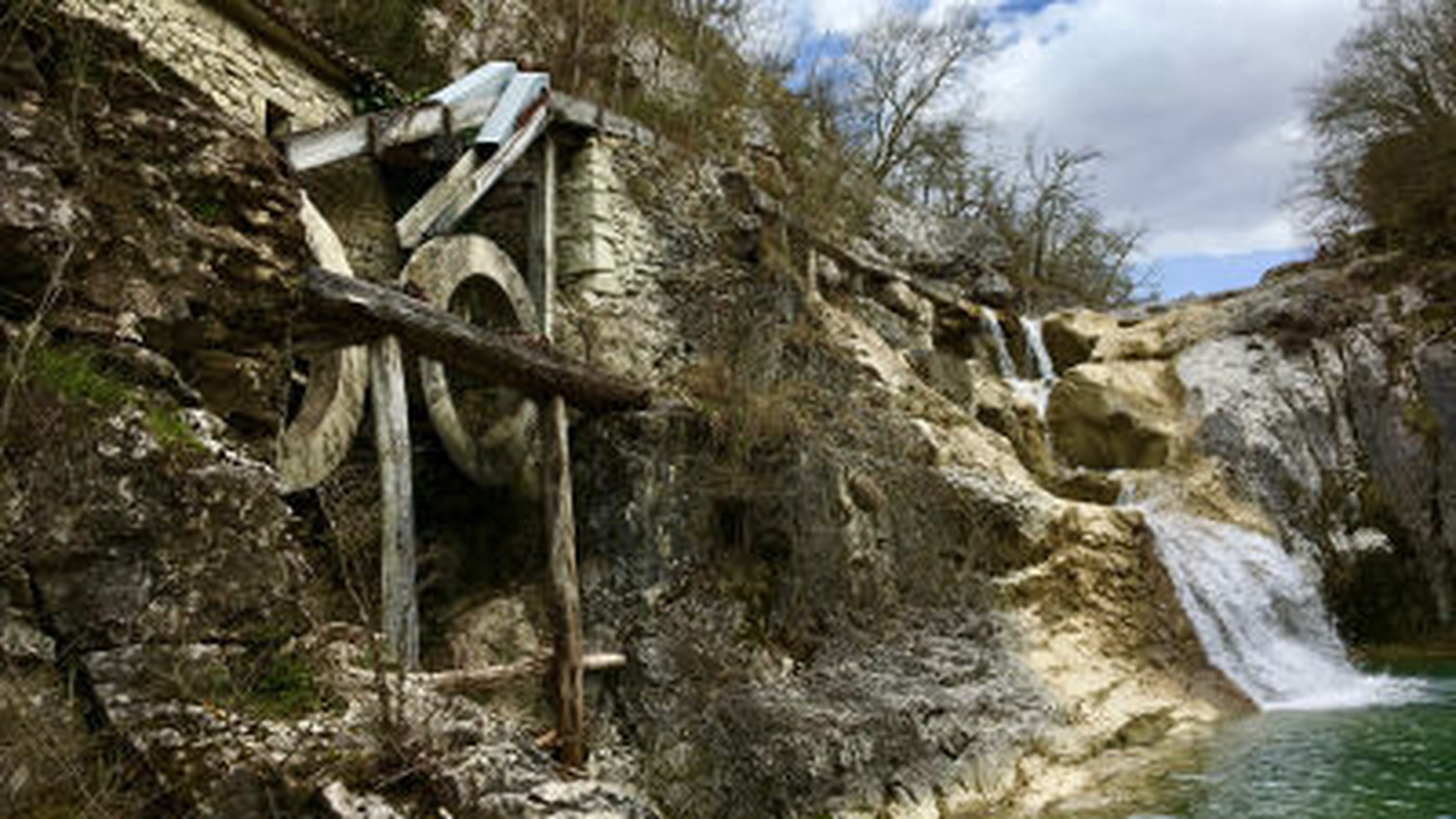 Ancient stone mill beside Kotli waterfall with wooden water wheel